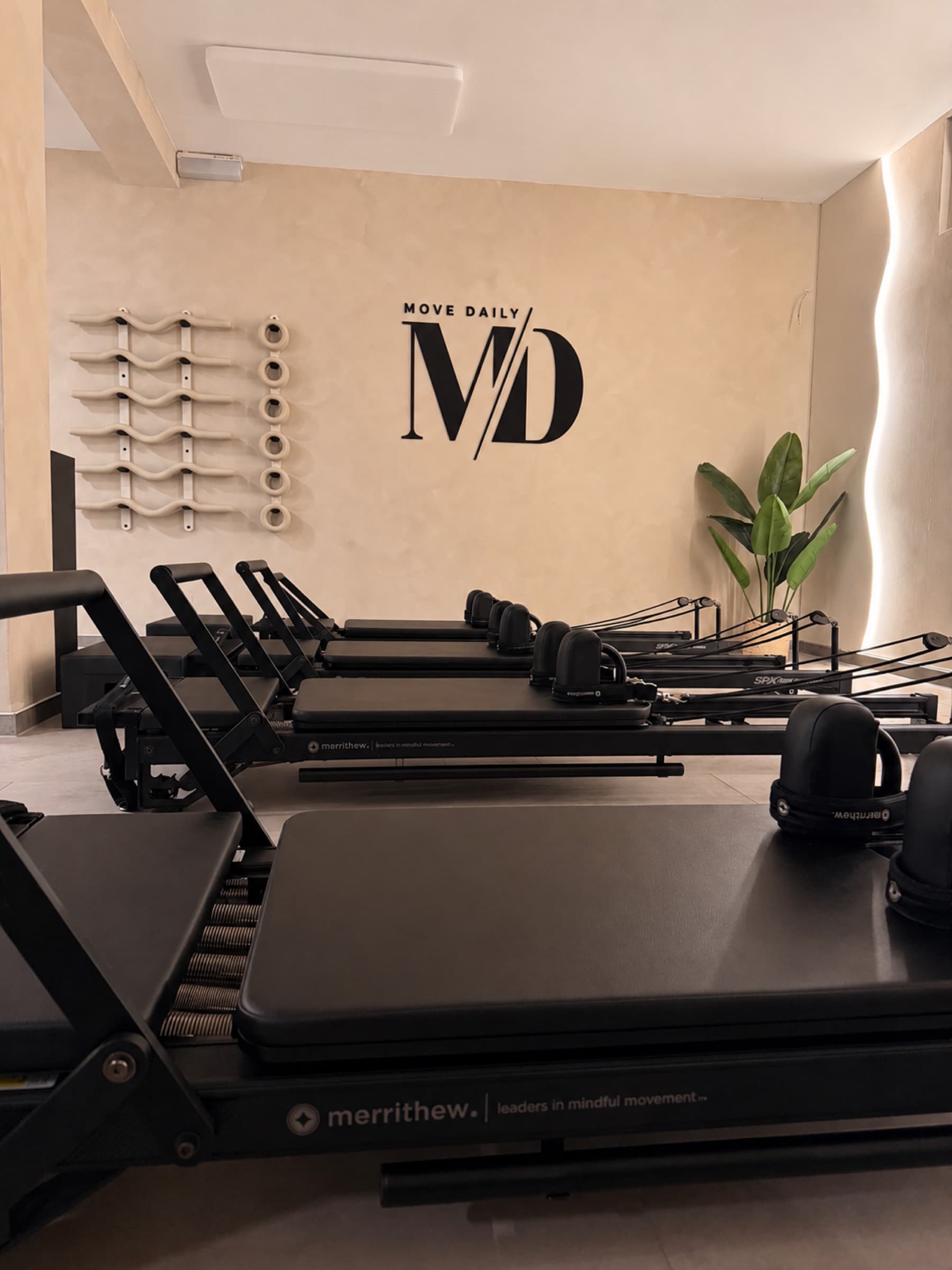 Reformer beds beneath the Move Daily MD logo wall